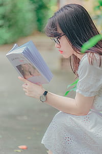 Woman Sitting While Reading Book Outdoors thumbnail