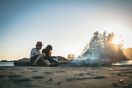 man and woman sitting at the beach during golden hour thumbnail