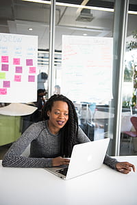 Woman in Gray Sweater Sitting in Front of Laptop Computer on Table thumbnail