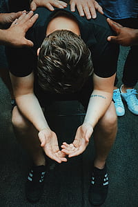 man surround by people sitting on chair looking downward thumbnail