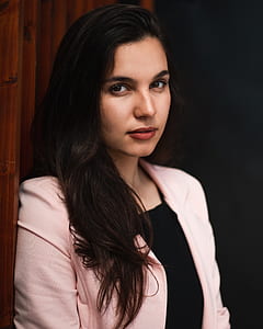 Woman in pink blazer lying on brown wooden wall thumbnail