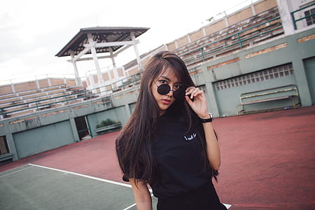 woman holding her sunglasses in tennis court during daytime thumbnail