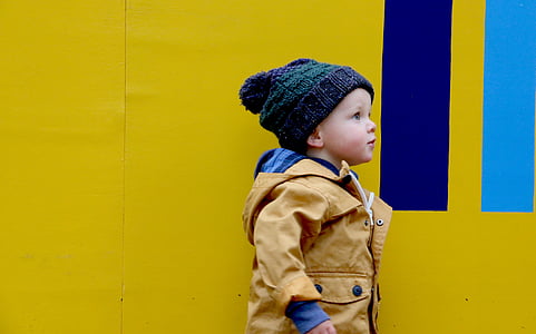 child standing beside yellow and blue painted walls thumbnail