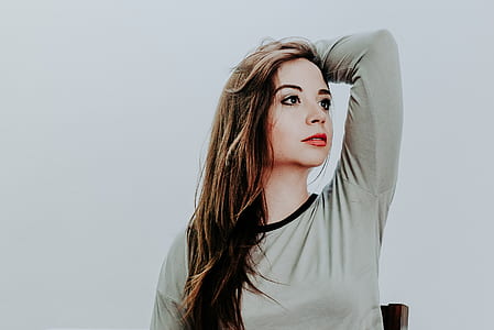 woman wearing gray long-sleeved shirt while standing near white painted wall thumbnail