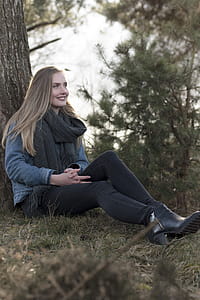 Woman Sitting on Ground Leaning Against Tree thumbnail