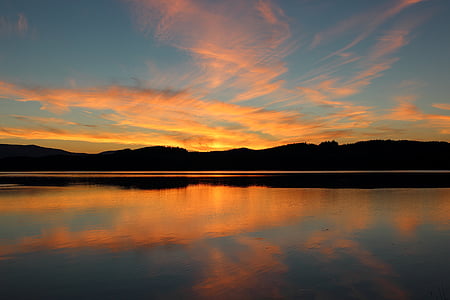 silhouette photo of body of water and mountains thumbnail