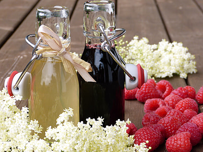 two clear glass bottles with liquid beside raspberries thumbnail