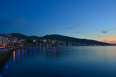 cityscape near body of water and mountain in background thumbnail