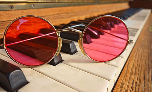 red round sunglasses with gold-colored frame on top of brown piano thumbnail