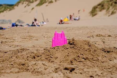 pink plastic castle toy on brown sand thumbnail