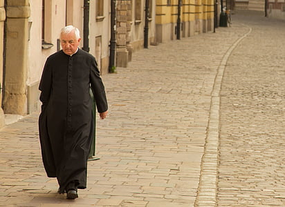 man wearing black cassock walking on gray concrete pavement during daytime thumbnail