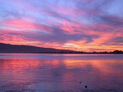 body of water under orange and gray sky thumbnail