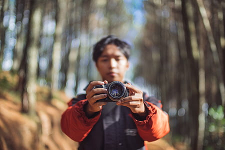 selective focus photography of man holding camera thumbnail
