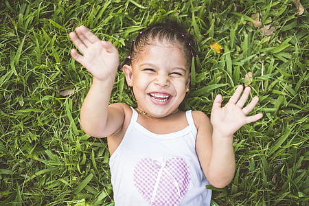high-angle photo of girl with white tank top lying on green grass field thumbnail