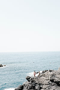 man standing on cliff near body of water thumbnail