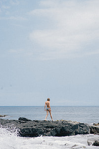 woman in bikini on rock structure covered with body of water thumbnail