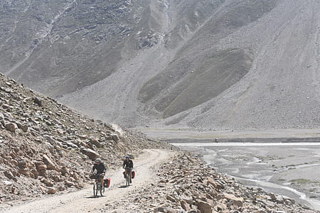 two people riding bicycles near mountain during daytime thumbnail