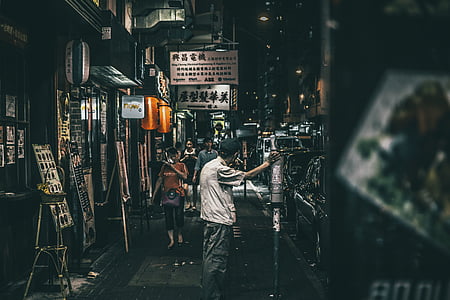 man leaning on post outdoor during night in tilt shift photography thumbnail