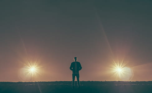 man standing on ground with two lights turned on thumbnail