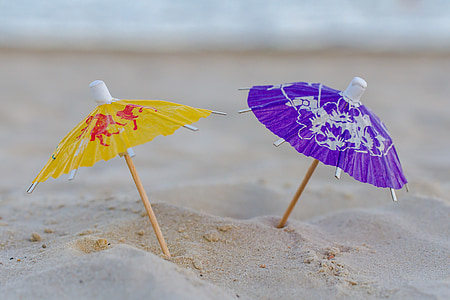 micro photography of two assorted-color mini umbrellas on sand thumbnail