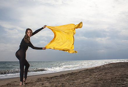 woman in black overall suit holding yellow textile thumbnail