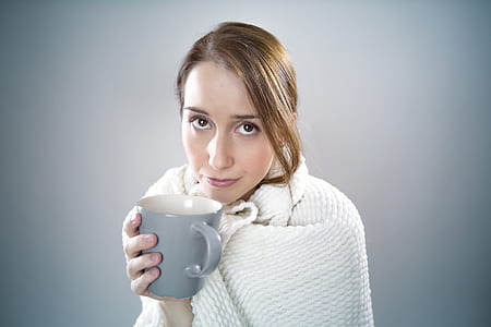 woman with white blanket holding gray ceramic mug thumbnail