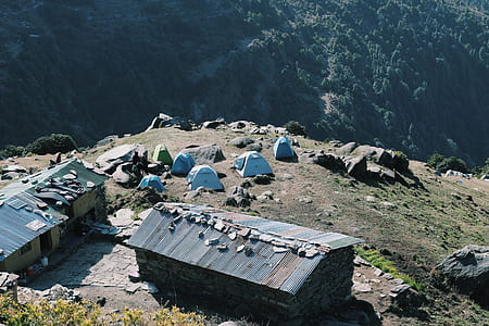 aerial photography of clothes lot on house roofs and tents on mountain during daytime thumbnail