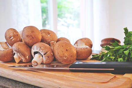 black handle knife beside mushroom and celery on top of brown chopping board thumbnail
