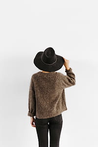 A woman in a brown sweater with a black hat on her head thumbnail