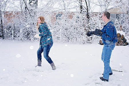man throwing snow ball to woman's back thumbnail