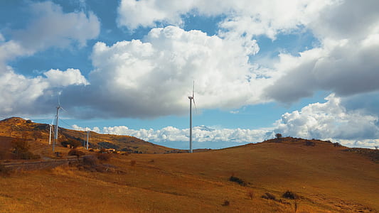 white windmill near road under cloudy sky at daytime thumbnail
