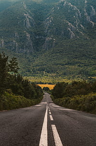 high-angle photo of concrete road overlooking green mounain thumbnail