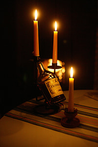 close-up photography of black and white label bottle beside pillar candles thumbnail