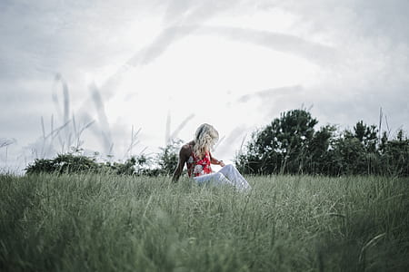 woman sitting on green grass field during daytime thumbnail
