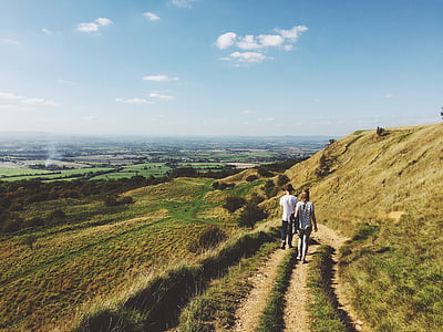 man and woman walking on pathway near green grass field at daytime thumbnail
