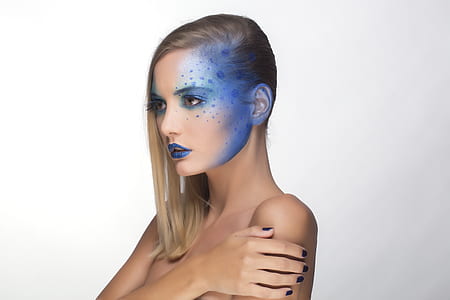 woman wearing blue lipstick and blue polka-dotted design the left side of her face thumbnail