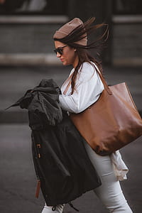 woman wearing white top holding coat thumbnail