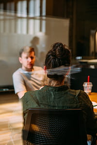 woman in collared shirt sitting in front of man and wooden table inside room thumbnail