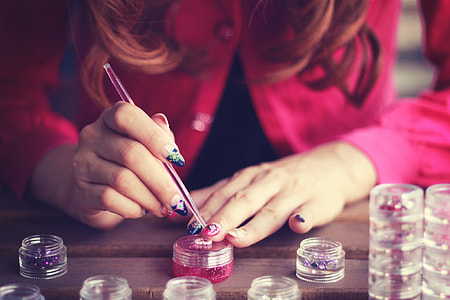 woman coloring her nail on brown wooden table thumbnail
