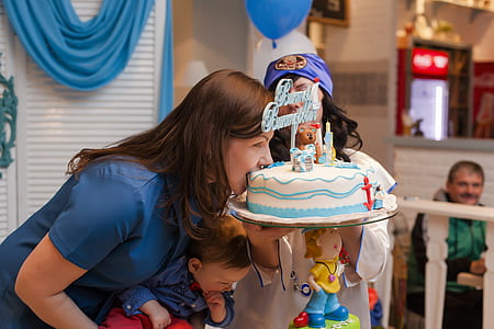 woman carrying baby while biting cake inside room thumbnail