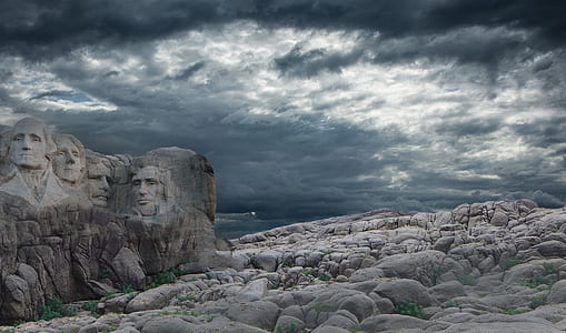 rock human head embossed mountain under gray and white cloudy sky during daytime thumbnail