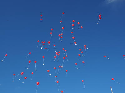 red balloons flying under clear blue sky during daytime thumbnail