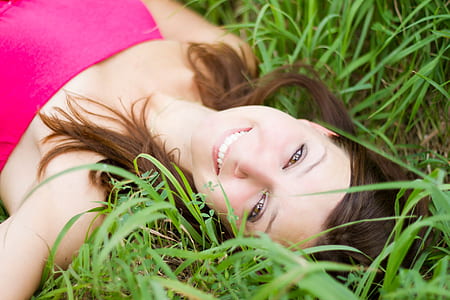 woman in pink strapless shirt lying on grass field during daytime thumbnail