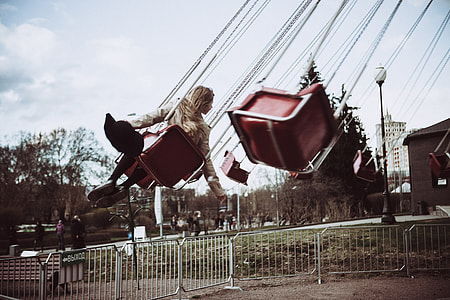 woman riding on flying swing during daytime thumbnail