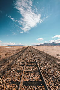 brown train rail under blue sky during daytime thumbnail
