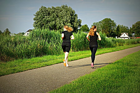 two women in black tops and bottoms running on grey trail thumbnail