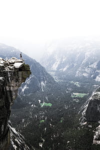man standing on the cliff of rock during daytime thumbnail