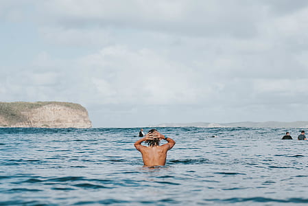 topless man on sea swimming during daytime thumbnail