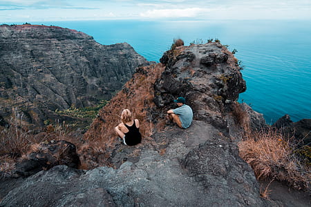 two person sitting on hill over body of water thumbnail