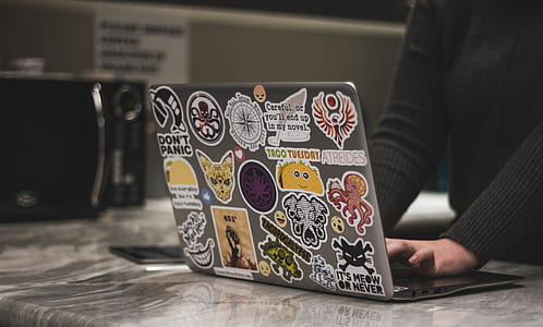 person wearing gray long-sleeved shirt using gray laptop computer on gray granite-top counter-top thumbnail